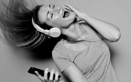 Black and white image of a woman enjoying music with white XX59 Headphones, her hair flowing with the rhythm, embodying the joy of sound.
