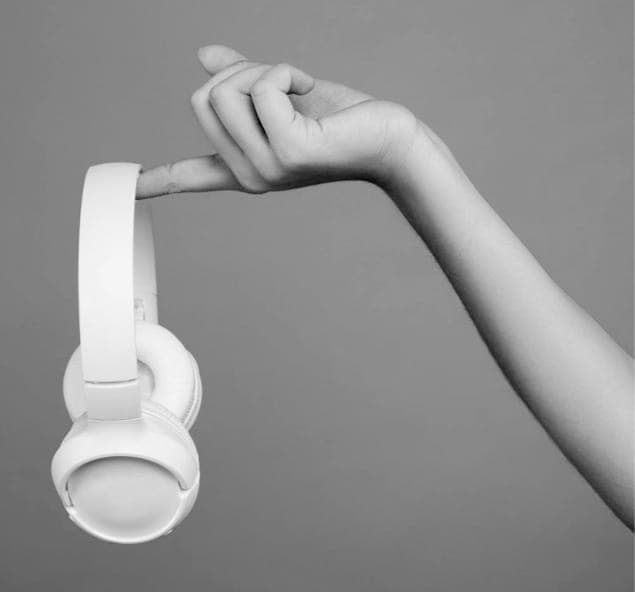Close-up of a woman's hand holding white XX59 Headphones.