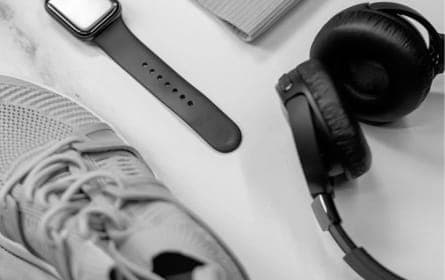 Pair of black XX99 Mark I Headphones resting on a white wooden table next to a black watch and white sneakers.