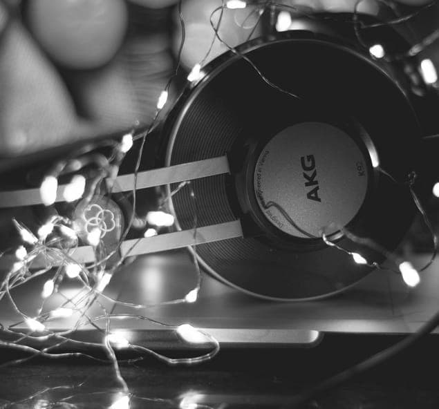 Black and white over-ear XX99 Mark I Headphones with Christmas lights wrapped around them, resting on a closed laptop computer.